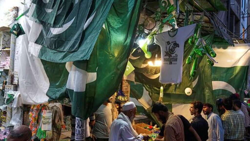 People shop for national flags and other items at a market in Lahore, Pakistan, Tuesday, Aug. 12, 2025, ahead of Independence Day celebrations. (AP Photo/K.M. Chaudary)
